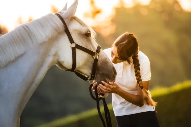 Frau gibt einem Pferd einen Kuss