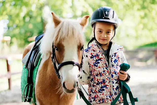 Kleines Mädchen führt ihr Pony